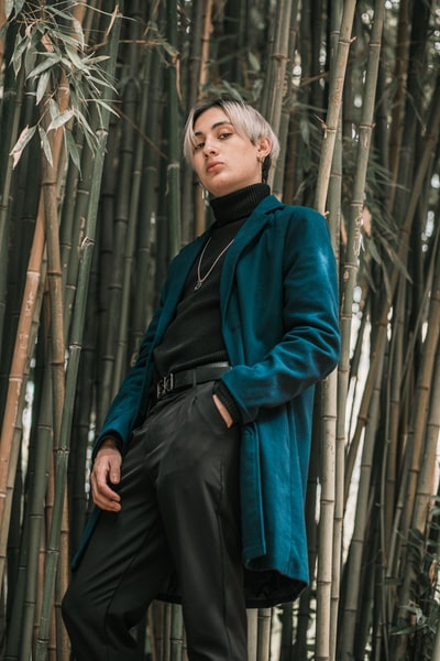 Standing on the bamboo fence beside the man in the red and black jacket
